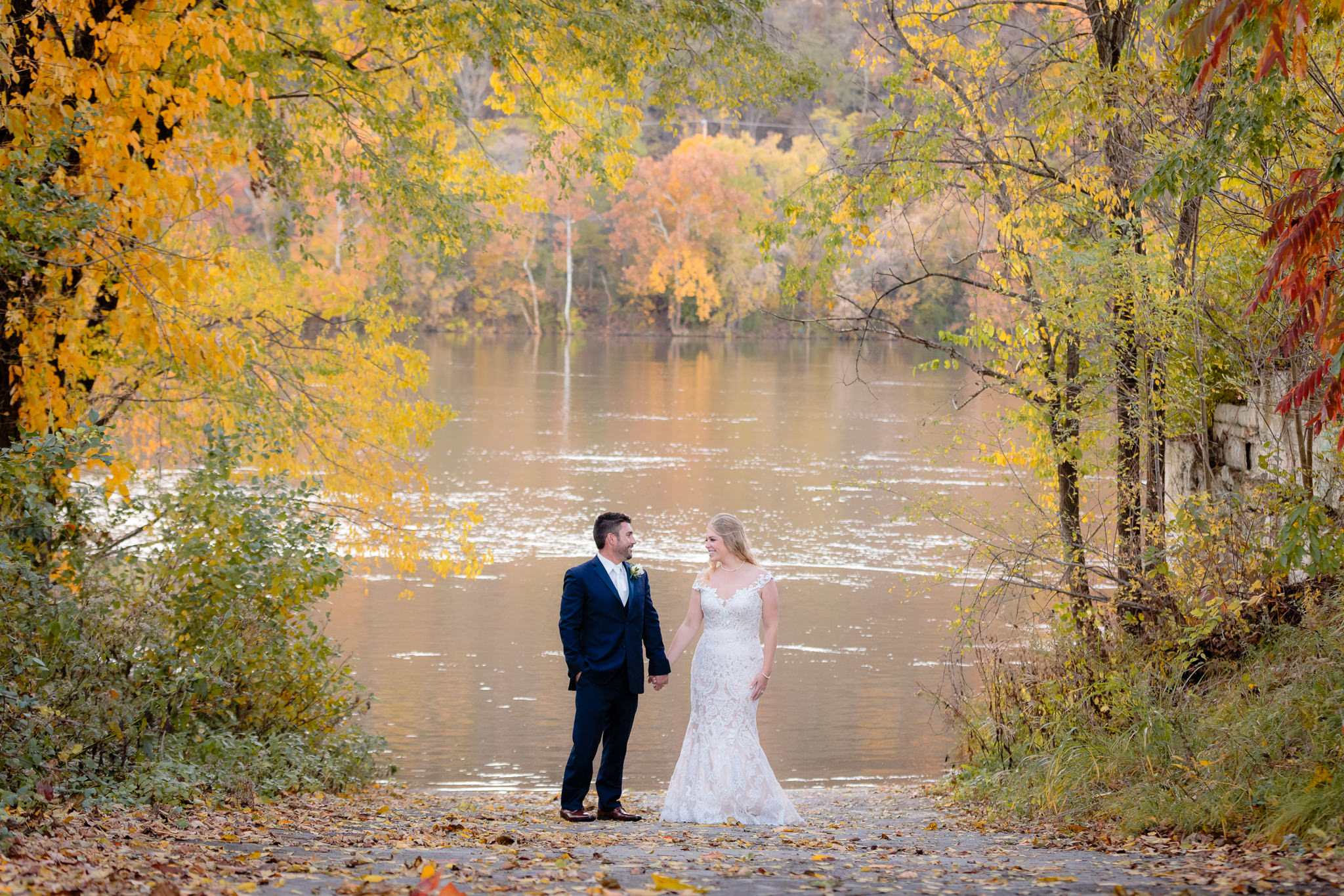 Bride & groom hold hands by the river before their Riverside Landing wedding