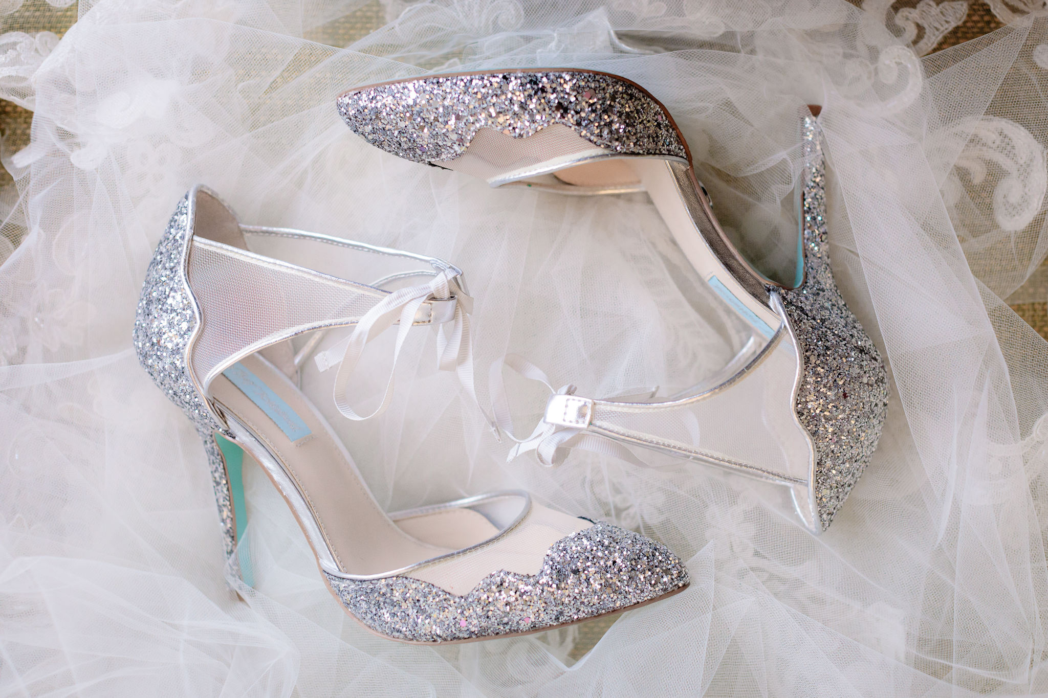 Silver glitter wedding shoes rest on a cathedral veil before a Soldiers & Sailors wedding