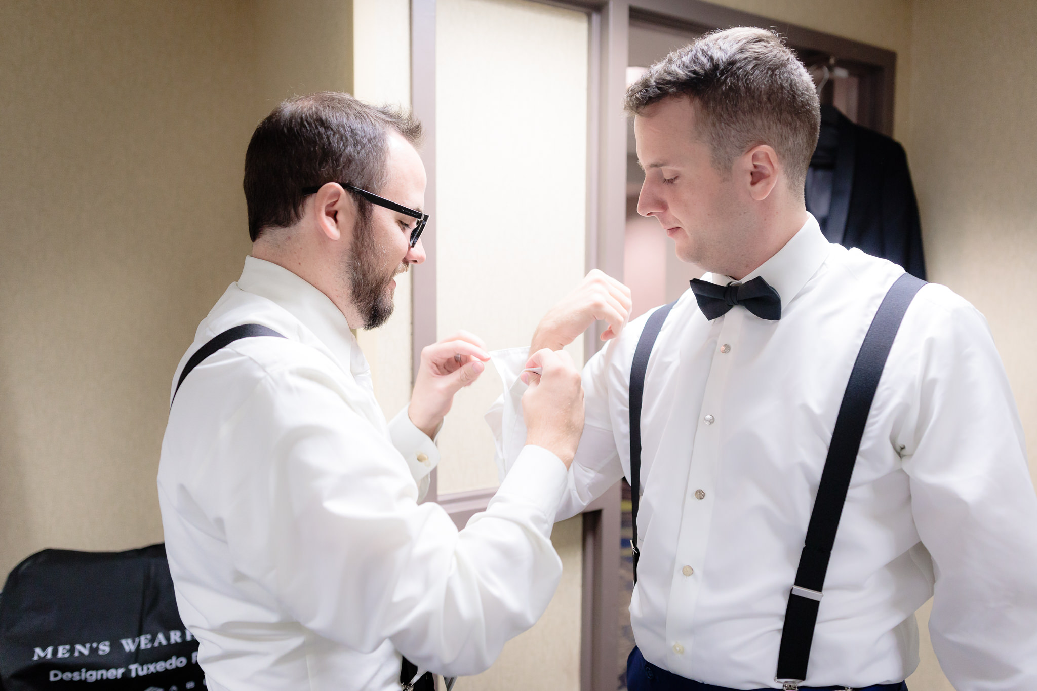 Groom's brother helps with his cufflink before a Saint Paul Cathedral wedding