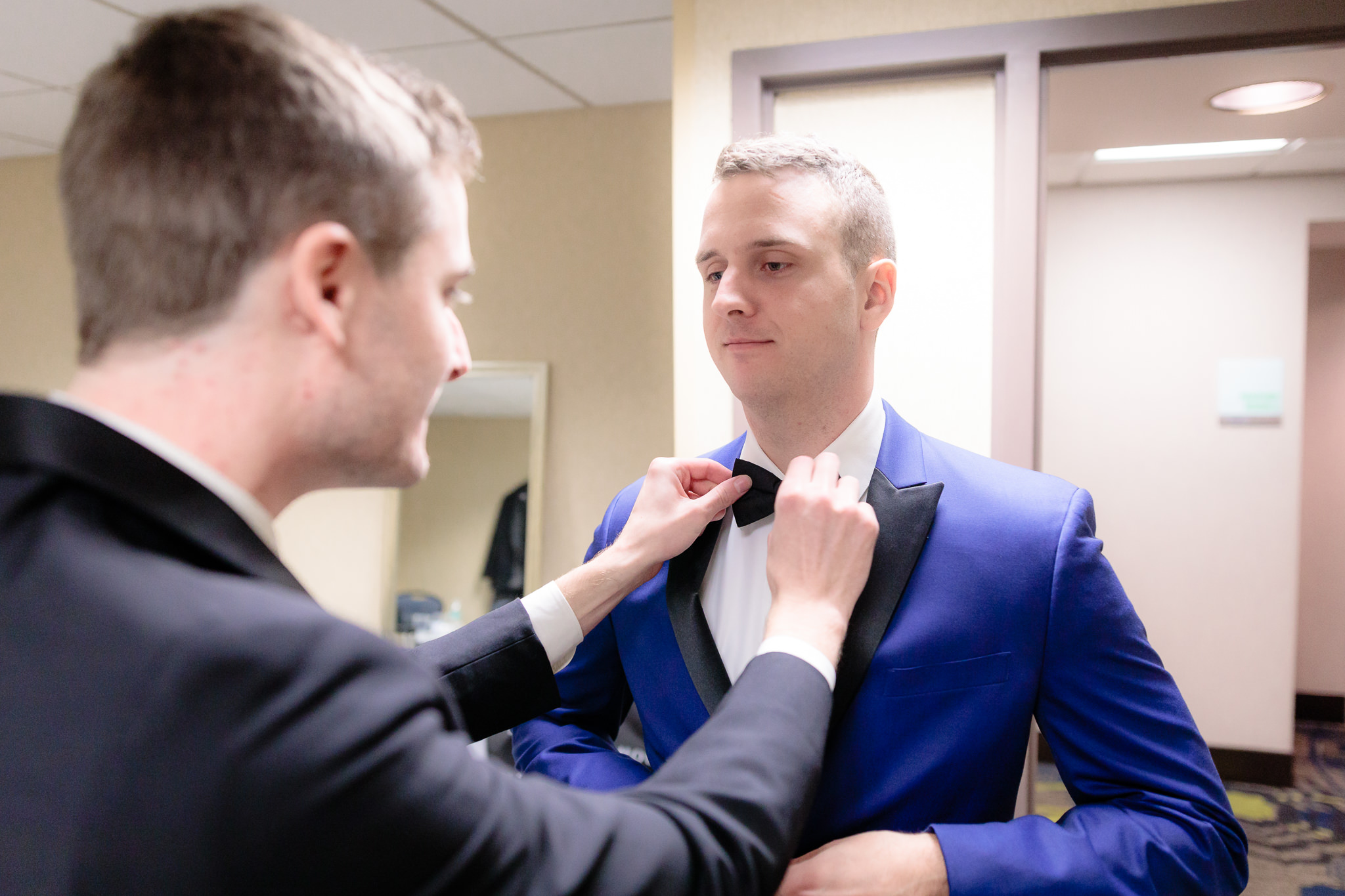 Best man straightens the groom's bowtie before a Saint Paul Cathedral wedding