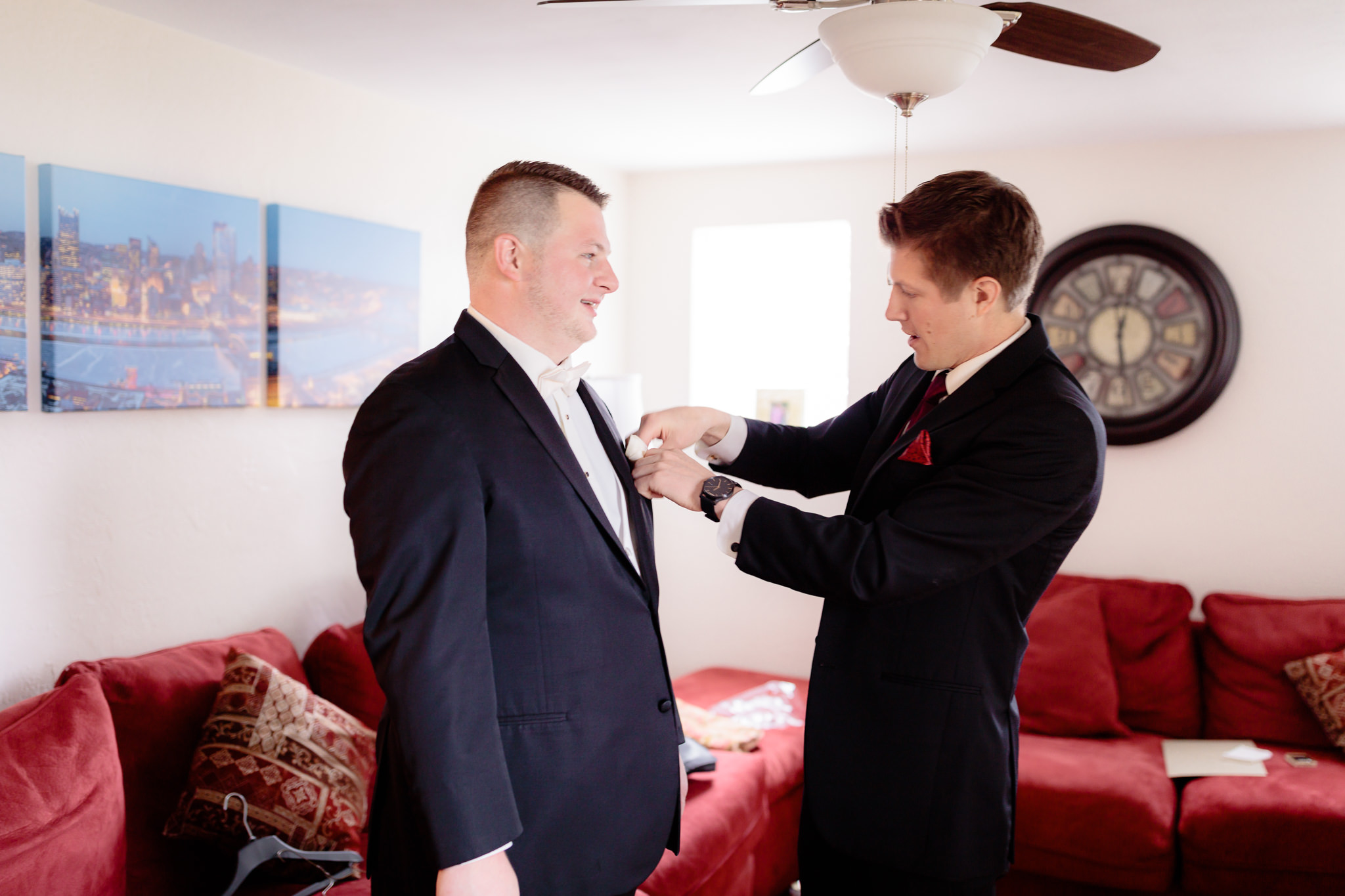 Best man puts pocket square in groom's tux jacket before a wedding at the Fez