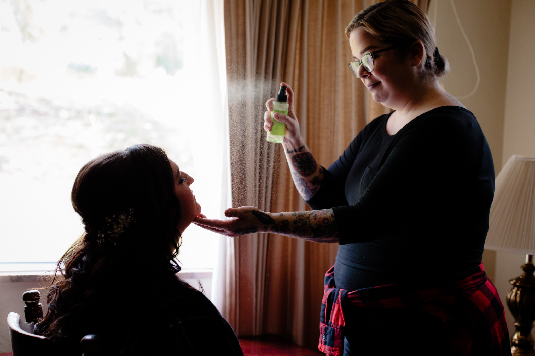 Brittney Morgan puts finishing spray on the bride's makeup before her wedding at the Fez
