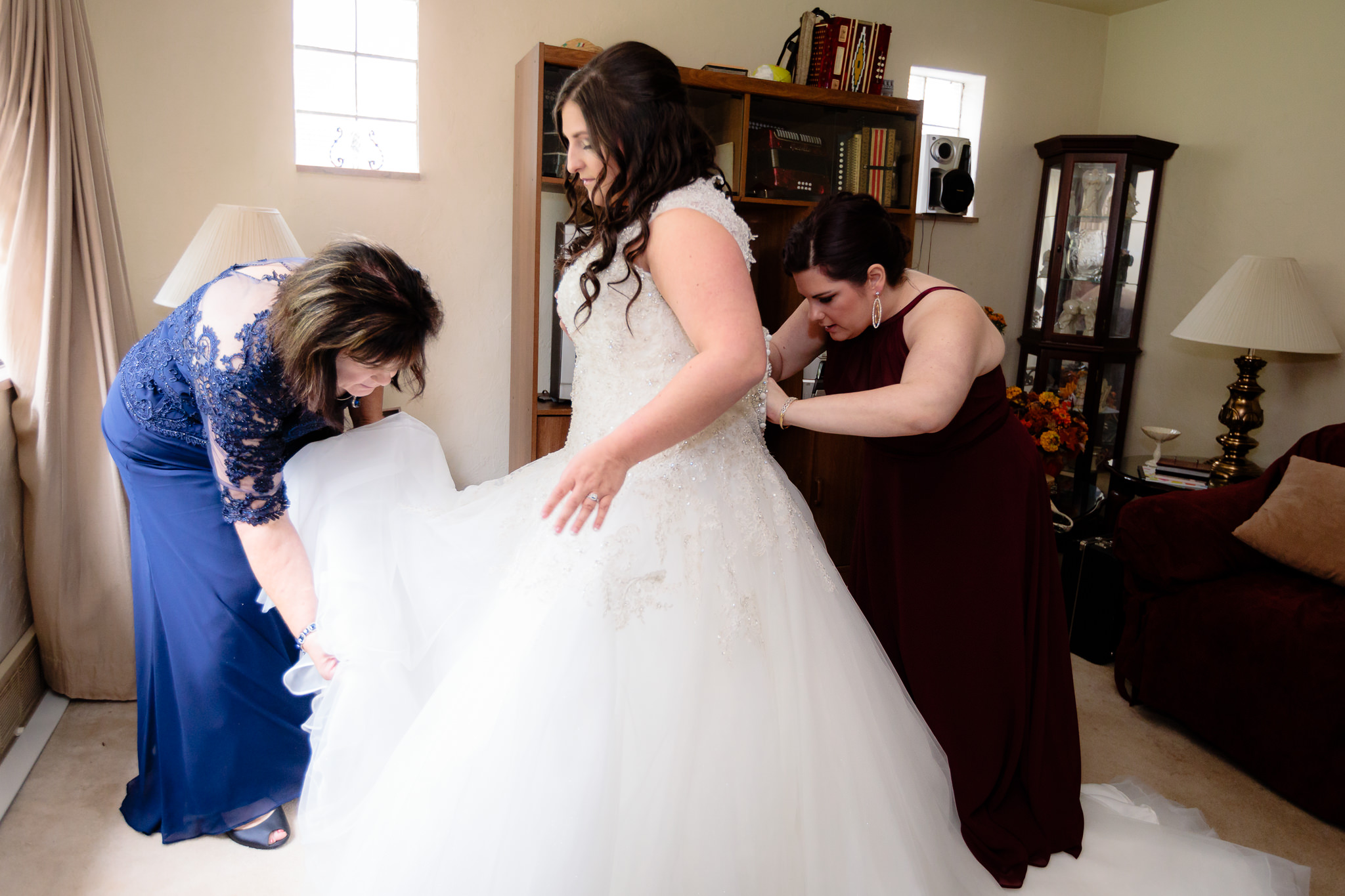 Bride's mom and sister help her into her Allure wedding dress