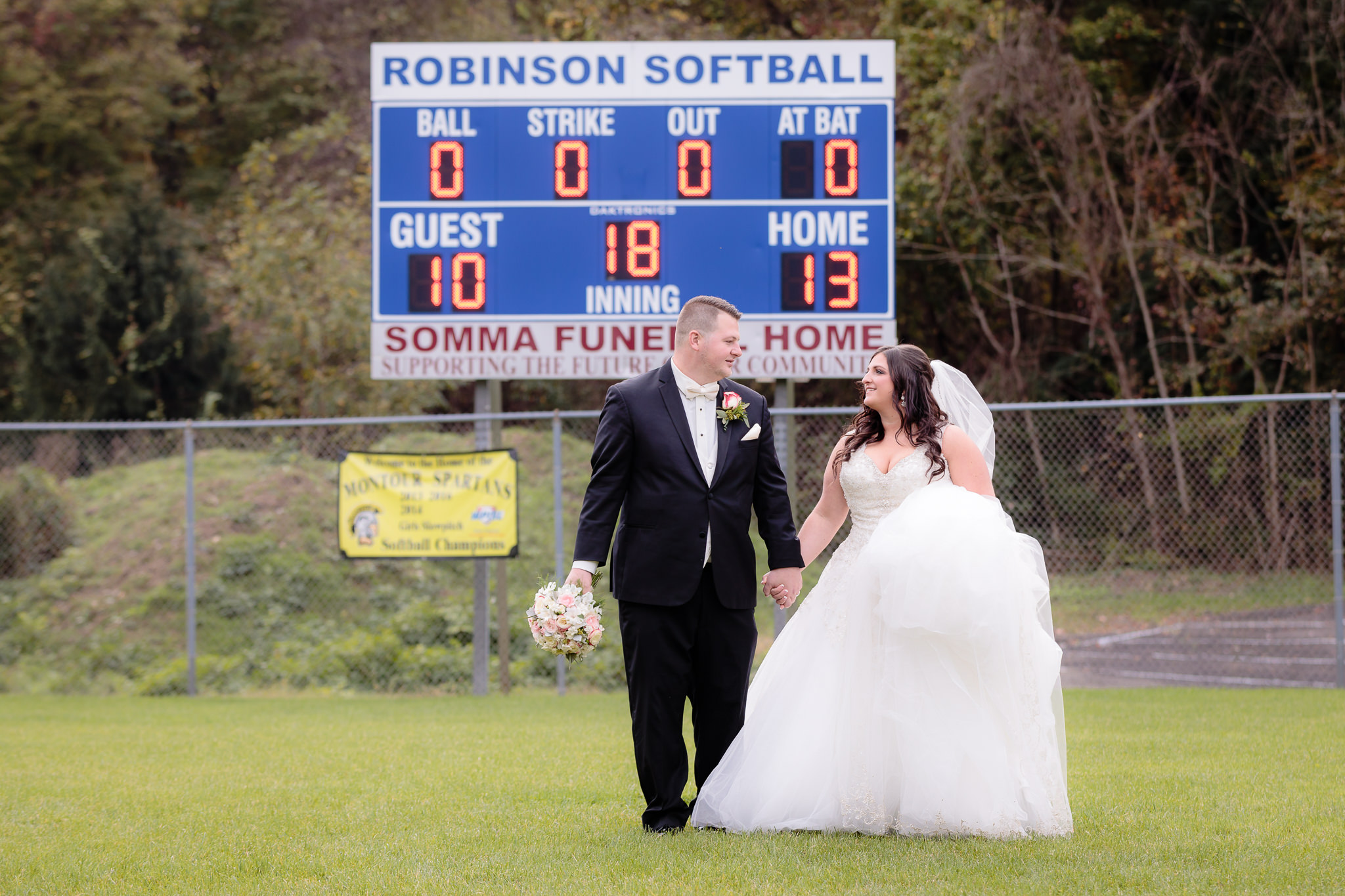 Newlyweds walk in the outfield of the Robinson Township Girls Softball field