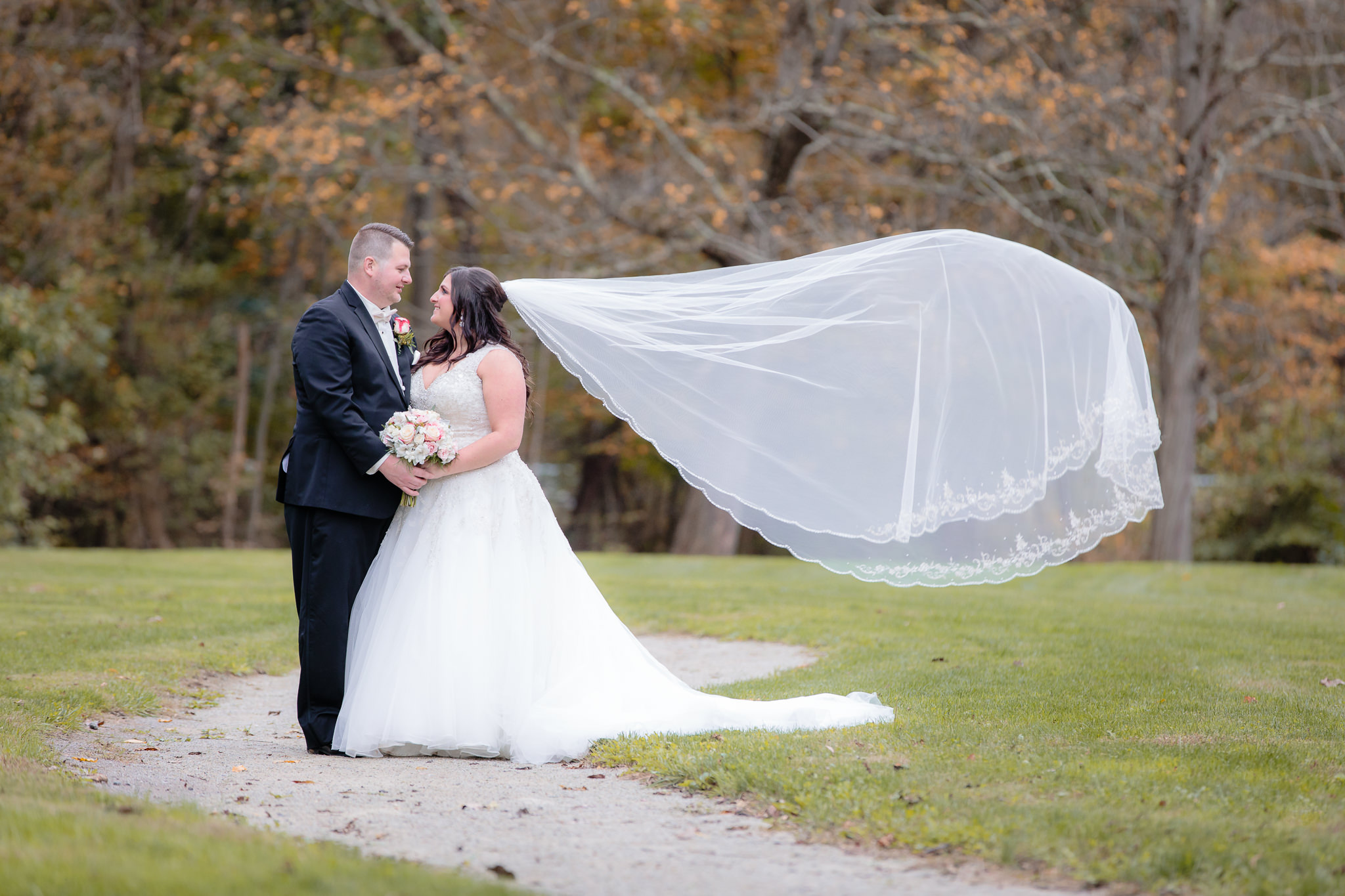 Bride's cathedral veil blows in the wind during portraits at Olson Park