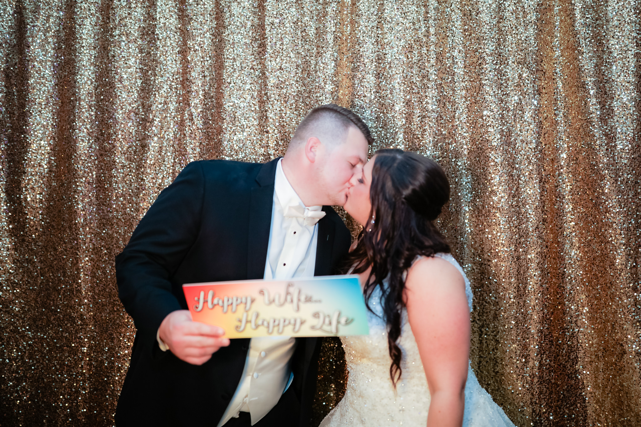 Bride and groom kiss inside the photo booth at their wedding at the Fez