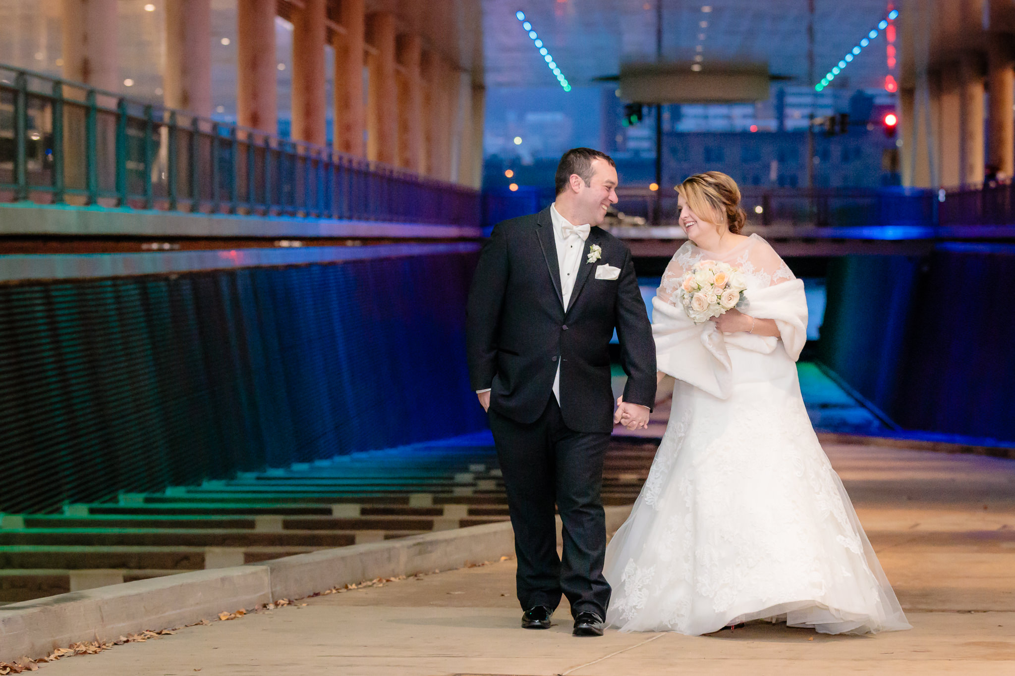 Newlyweds laugh as they walk through the colorful David L. Lawrence Convention Center walkway