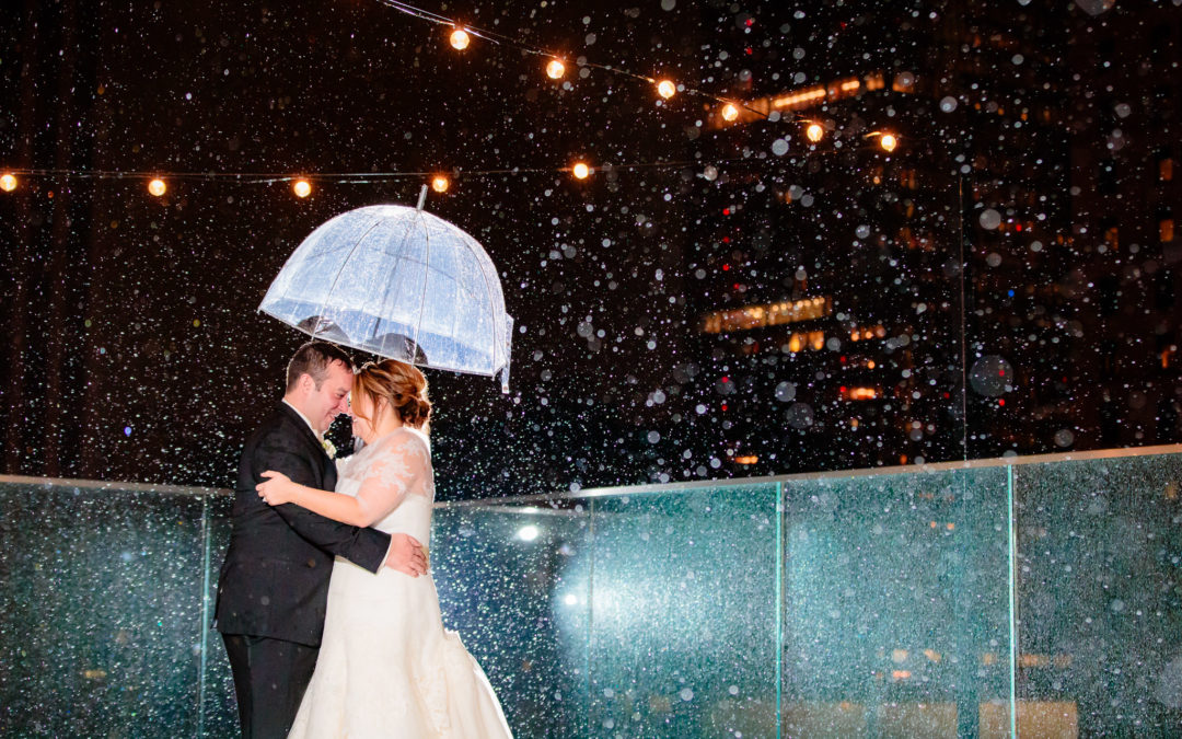 Newlyweds in the rain under a clear umbrella on the roof of Hotel Monaco Pittsburgh
