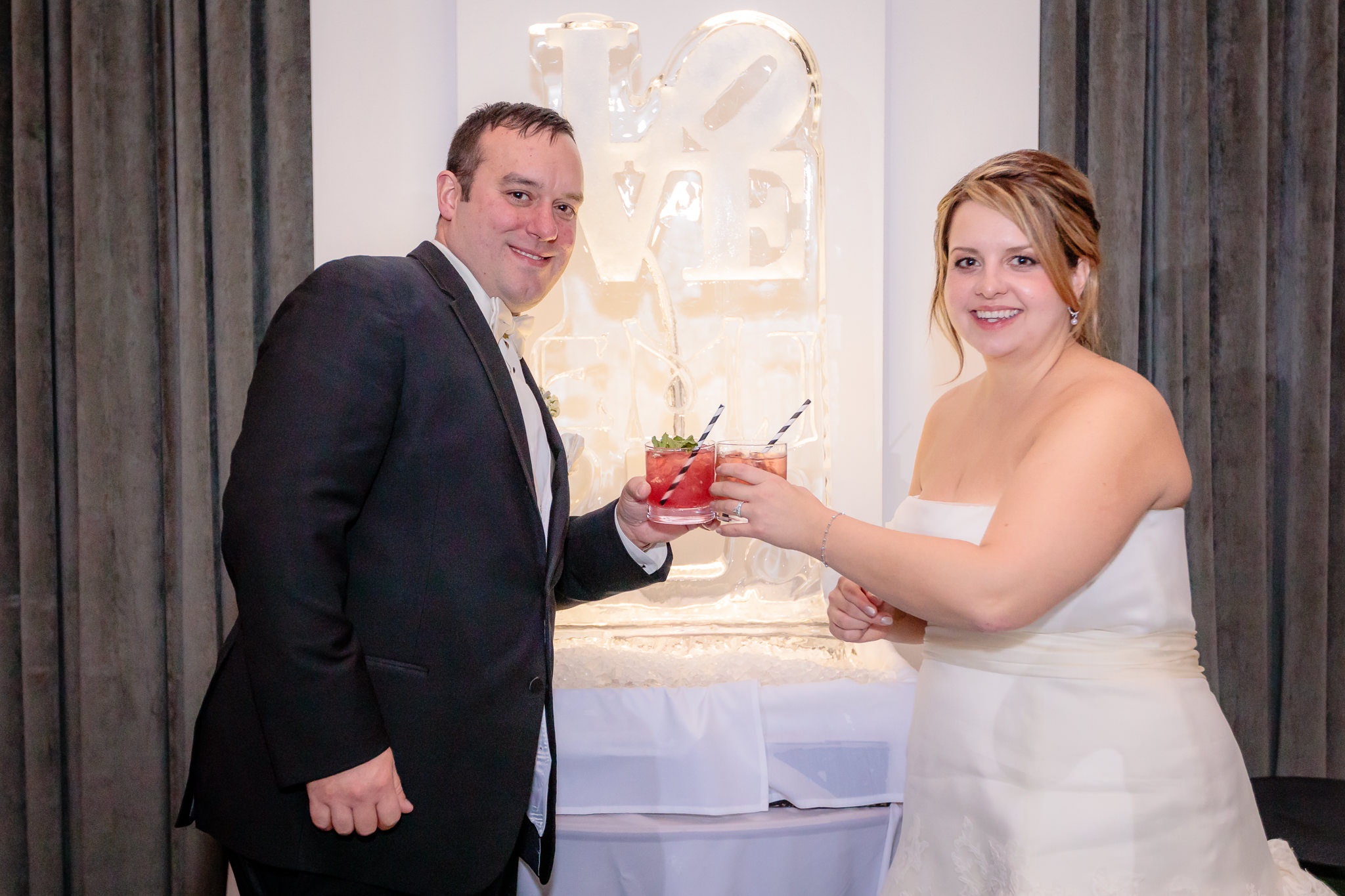 Newlyweds hold cocktails from an ice luge at their Hotel Monaco wedding