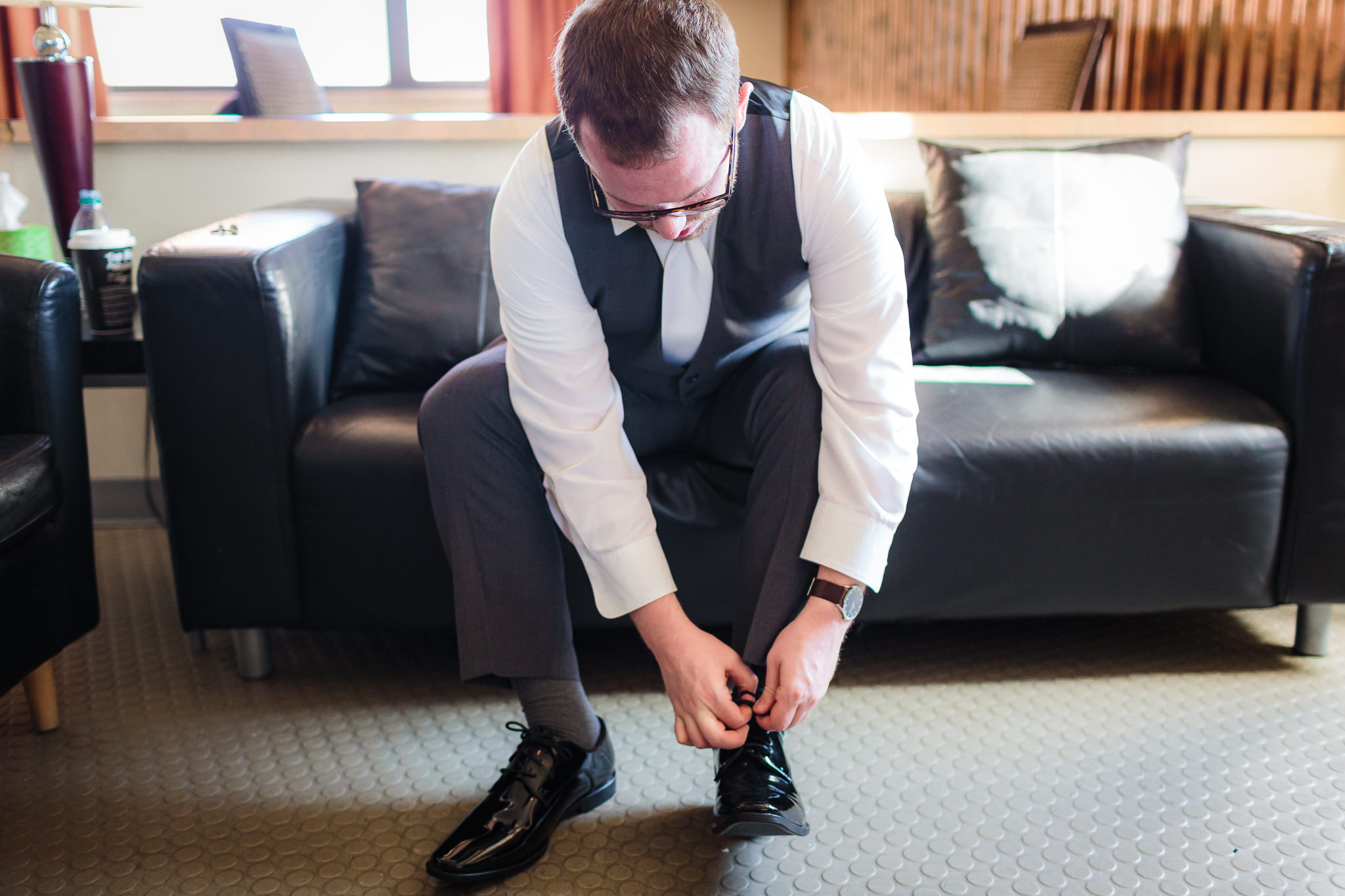 Groom ties his shoe getting ready for his wedding at the DoubleTree Pittsburgh Downtown
