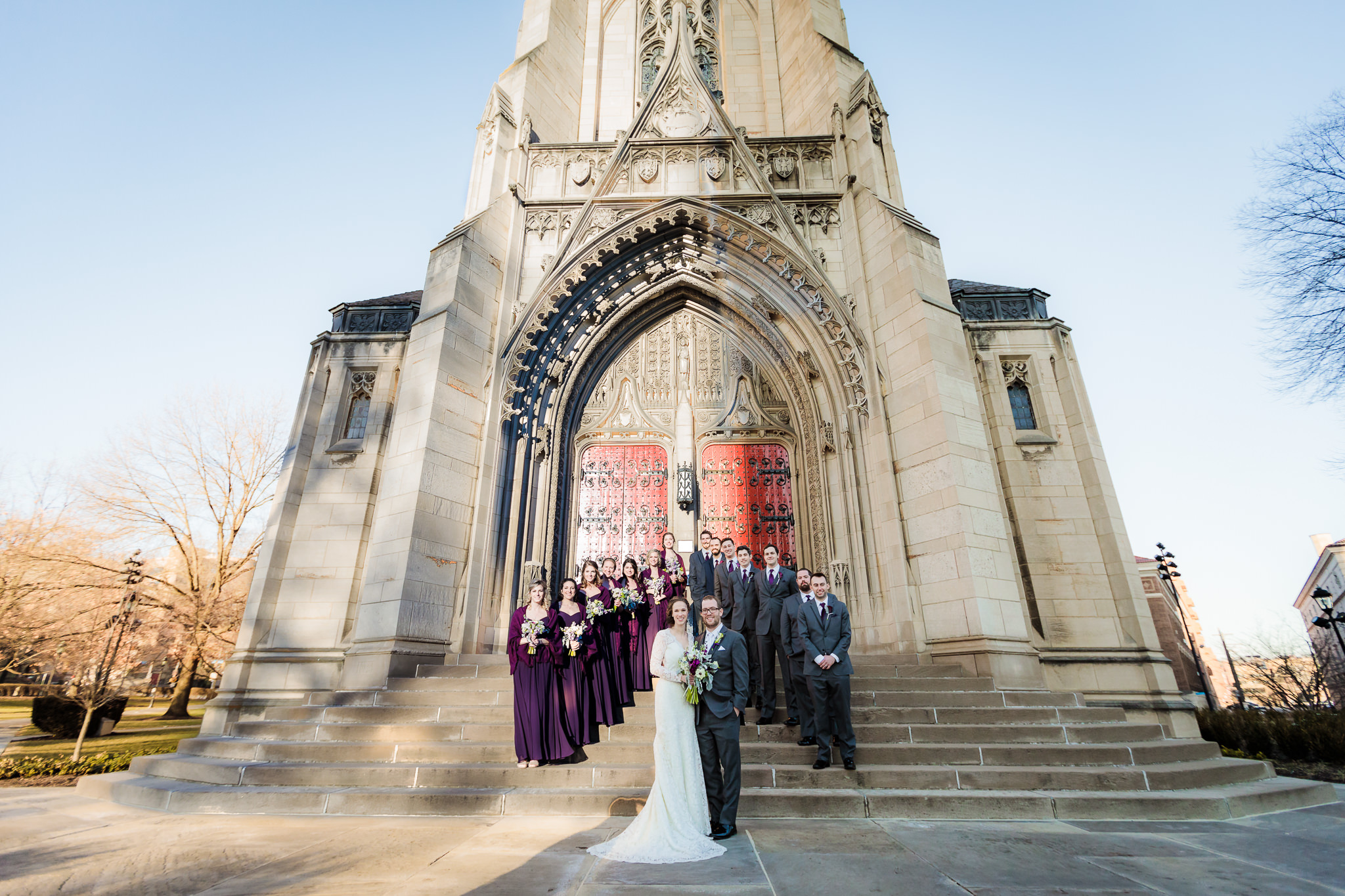 Bridal party on the steps in front of the red doors of Heinz Chapel in Pittsburgh