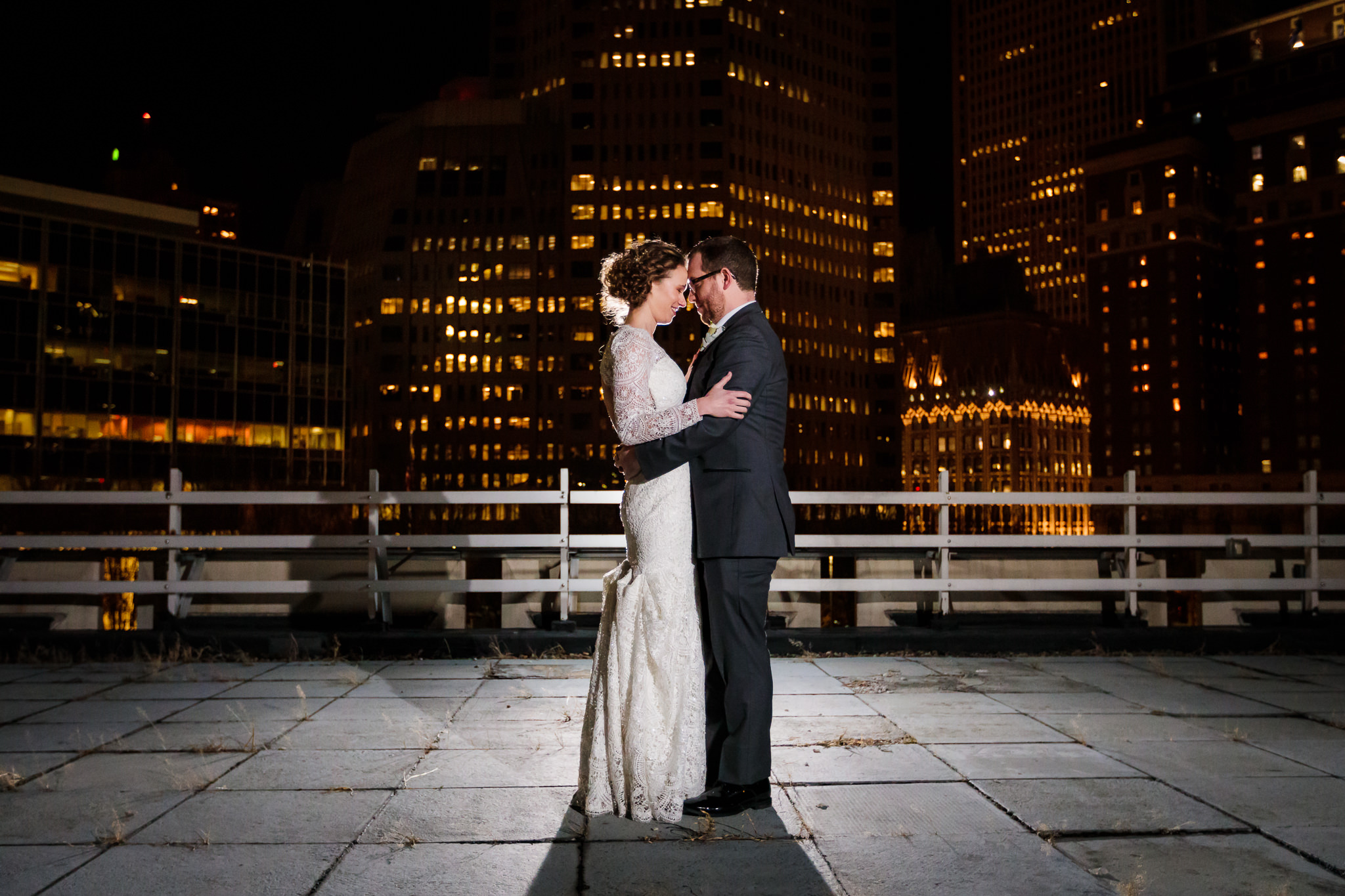 Bride & groom pose for a photo at night on the rooftop patio of the DoubleTree Pittsburgh Downtown