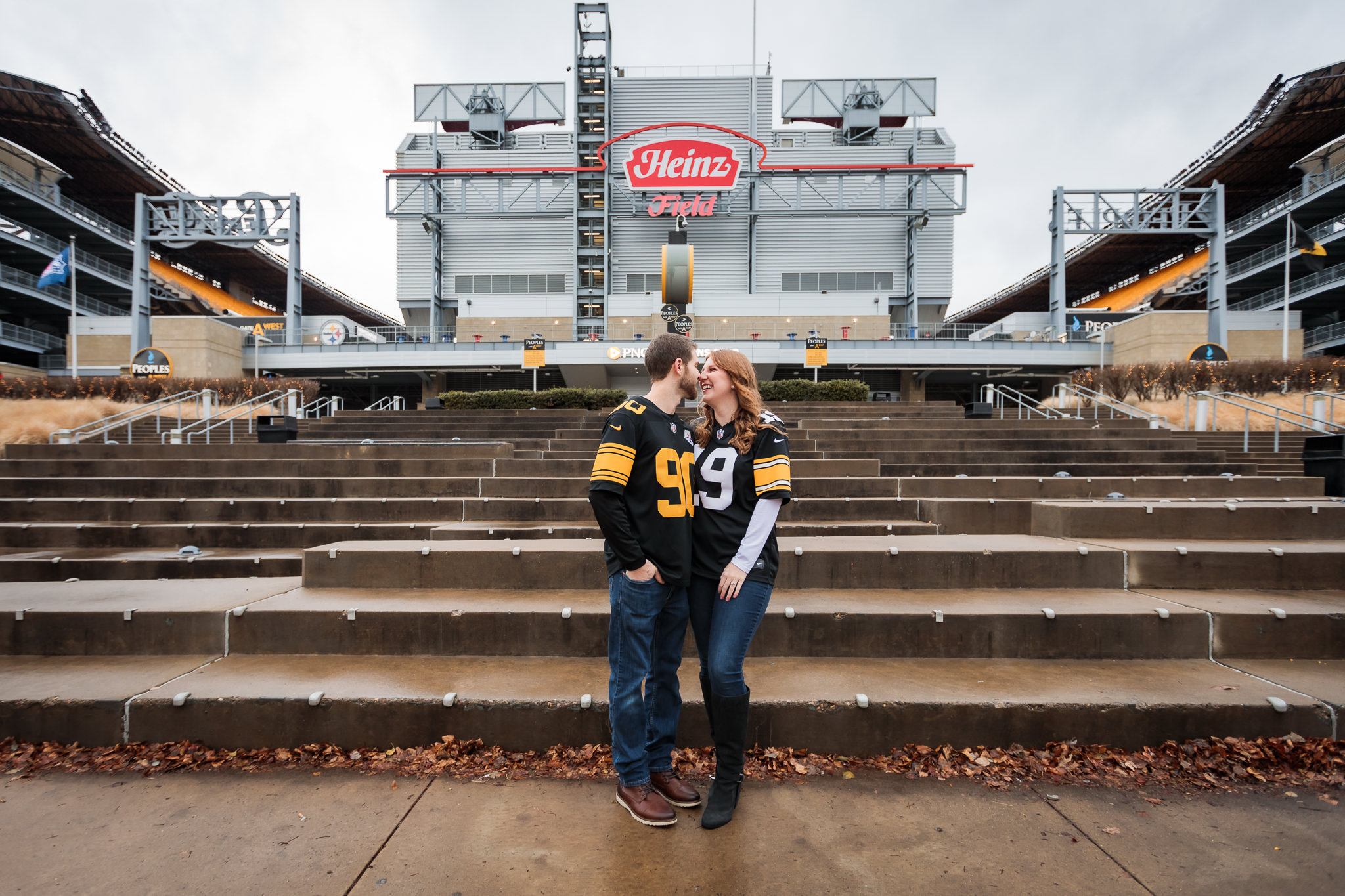 Engaged couple wearing Steelers jerseys in front of Heinz Field in Pittsburgh, PA