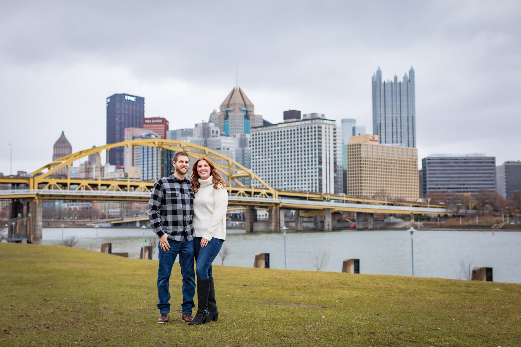 Engaged couple in front of Pittsburgh skyline at a North Shore engagement session