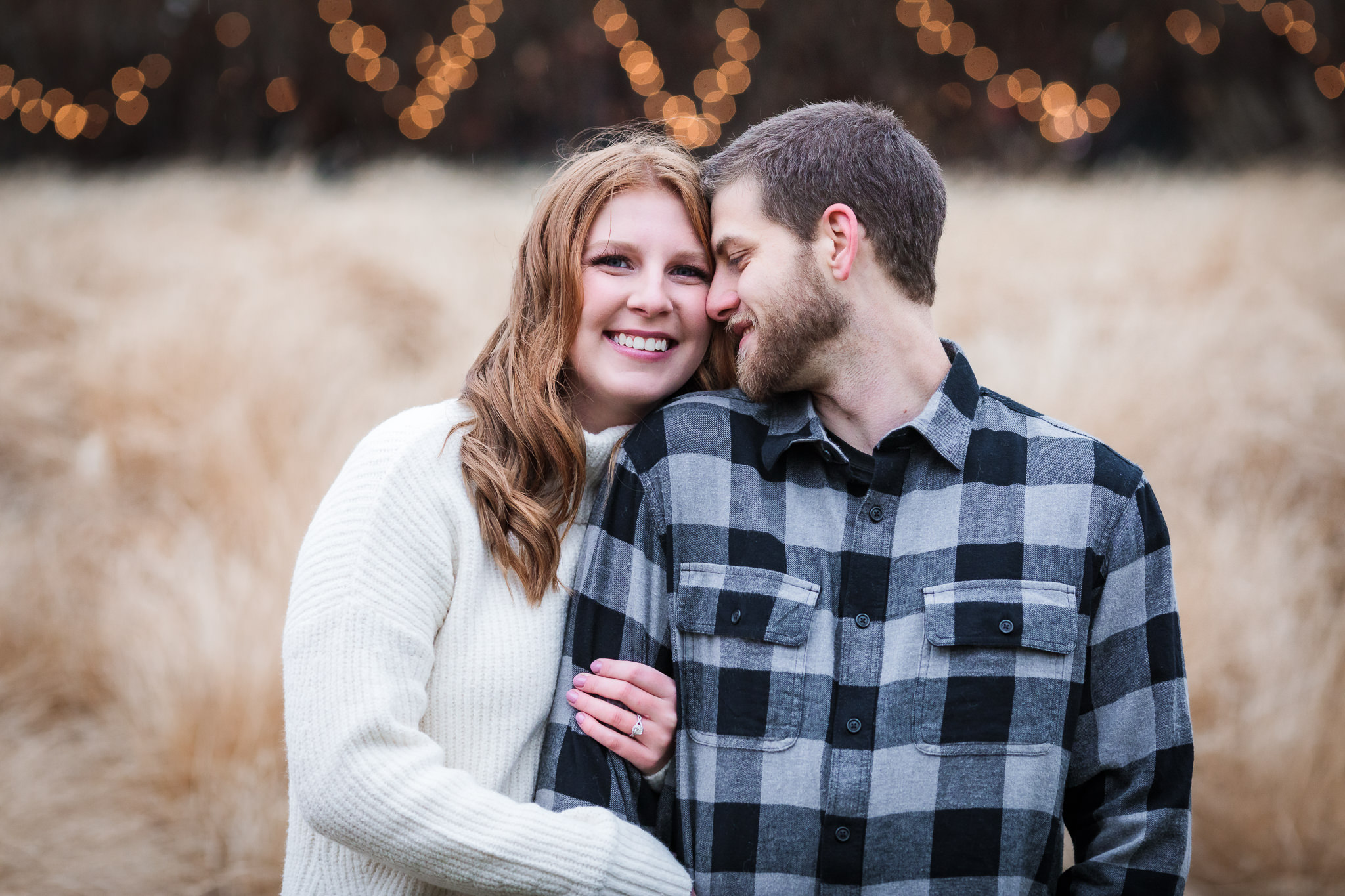 Couple in front of tall grasses and Christmas lights at a North Shore engagement session